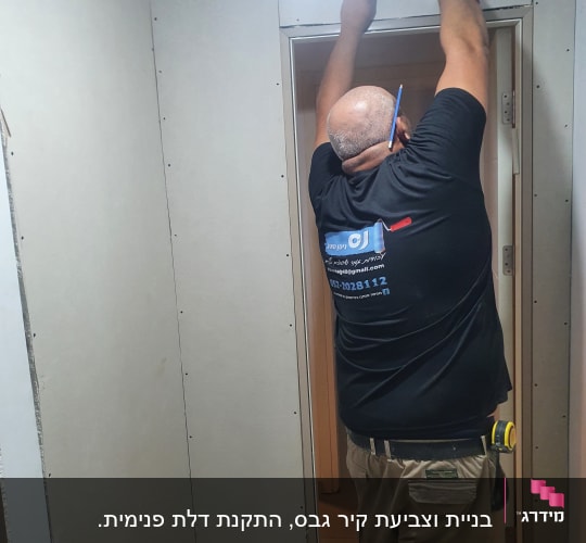 אדם מתקין לוח גבס עם מברגה
